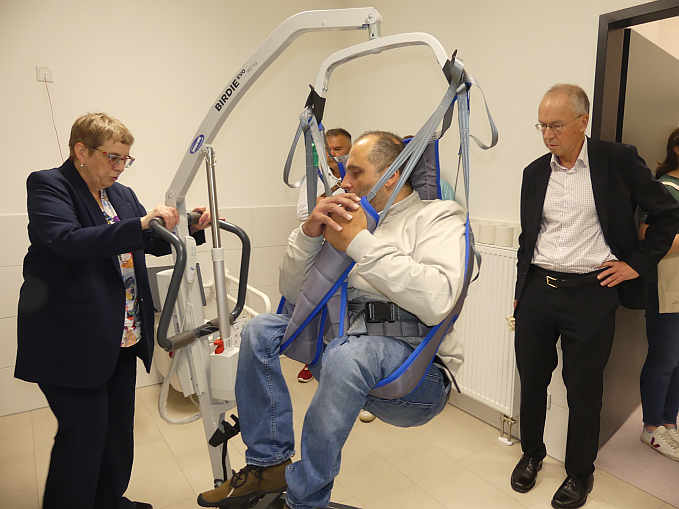 Schritt 3: sicher im Hebetuch sitzend, geht es schwebend mit dem mobilen Patientenlifter zur Pflegeliege...<br>Foto: © Mara Sander