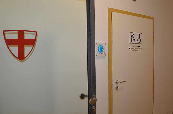 Nur eine Glastür von der Tourist-Information getrennt. Ein Schild weist den Weg zur »Toilette für alle« im Innenstadtrathaus.<br />Foto: © Mara Sander