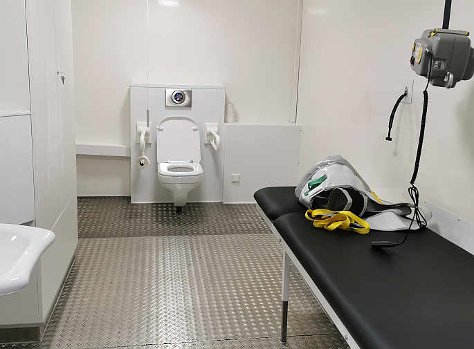 Die mobile Rollstuhl-Toilette ist zusätzlich ausgestattet mit einer Wandklappliege, einem Deckenlifter (Hebetuch vorhanden) und einem luftdicht verschließbaren Windeleimer<br>Foto: © Beate Gärtner